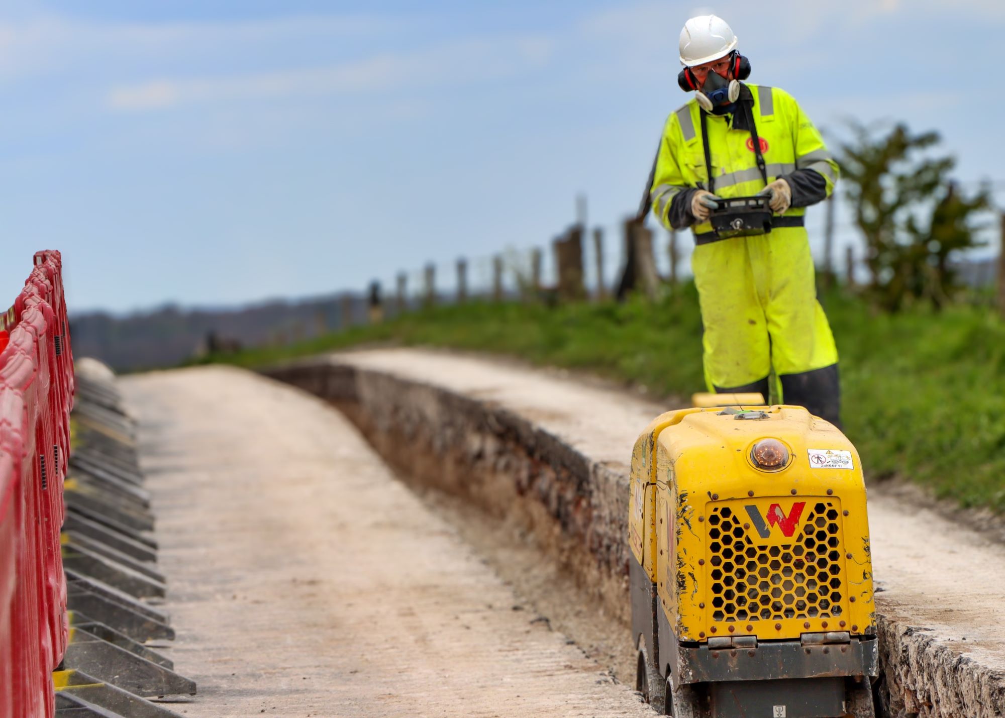 A machine digging a trench in a road ahead of cable laying works