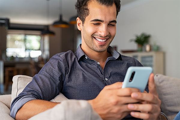 Smiling man looking down at his mobile phone.